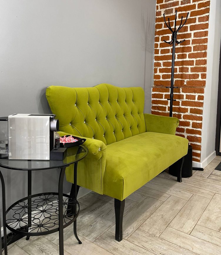 Уютная зона ожидания в студии бровей и ресниц: диван и кофе